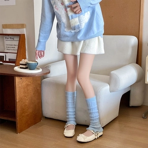 Close-up of sky blue cable knit leg warmers with ribbed cuffs and textured wool pattern