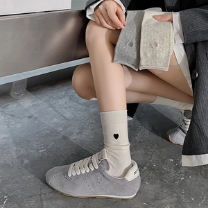 Detail of embroidered heart patterns on striped knit mid-calf socks in soft neutral tones