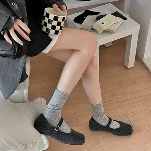 Close-up of embroidered striped socks paired with dark grey Mary Jane shoes and metal buckles