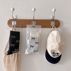 Detail von Ballettsocken mit Schleifen und bestickter Baseballkappe an einer Holzleiste