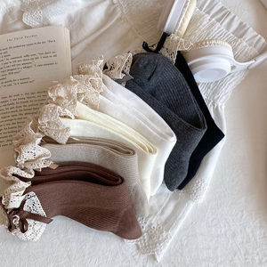 Flat lay of cotton crew socks with lace trim and bows in vintage earth tones