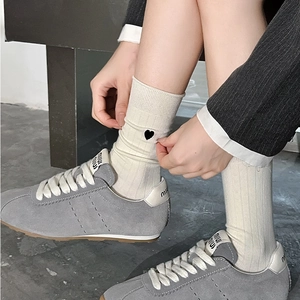 White vertical ribbed socks with black heart embroidery paired with gray suede sneakers