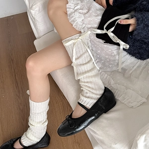Gros plan de jambières en tricot blanc avec rubans satin et ballerines noires