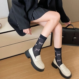 Detail von cremefarbenen Plateauschuhen mit schwarzen Socken mit Schleifenmuster