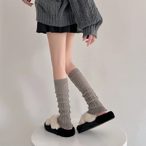Detail of grey knitted leg warmers with vertical stripes and ruffled cuffs