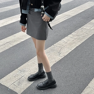 Close-up of black matte platform loafers paired with grey vertical striped crew socks