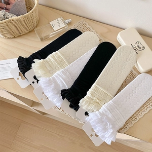 Détail de la dentelle et du nœud des chaussettes résille en lot de 5 sur bois clair