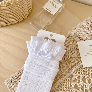 Détail de chaussettes en dentelle blanche avec bords à volants et petit nœud