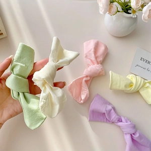 Close-up of pastel velvet bow socks in various macaron colors on a clean desk background