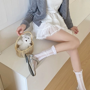 Close-up of white lace hollow knee-high socks with ruffled edges and silver Mary Jane shoes
