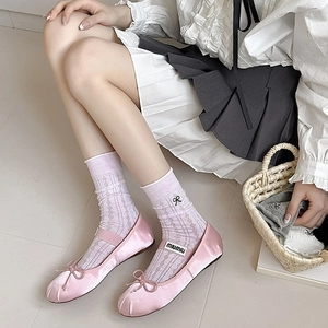 Close-up of pink mesh socks with black bow embroidery and ribbon ballet flats