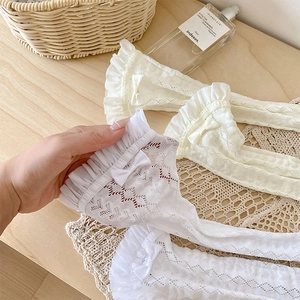 Détail de chaussettes en dentelle blanche avec froufrous à nœud et motifs en cœur