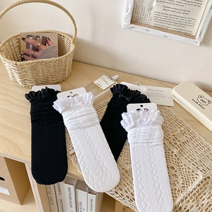 Détail de chaussettes hautes en maille respirante avec bords à volants et nœuds