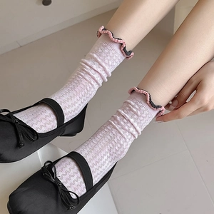 Close-up of pink mesh socks with ruffled cuffs worn with black Mary Jane shoes