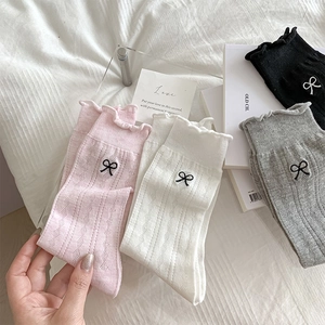 Close-up of ballet-style mesh socks with delicate bow embroidery and frilly cuffs