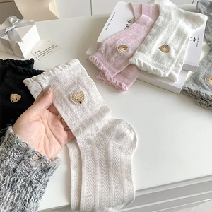Détail de dentelle à volants et broderie d'ours sur chaussettes en coton résille