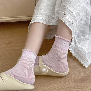 Nahaufnahme hellrosa Socken mit Spitzenrand, Schleifenstickerei und Pünktchen-Muster