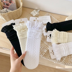 Détail de chaussettes en dentelle ajourée avec nœuds et bords à volants doubles
