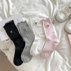 Close-up of ballet style bow embroidery and mesh diamond texture on mid-calf socks