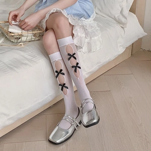 Detail of white Lolita calf socks featuring oval hollow cut-outs and black ribbon bows