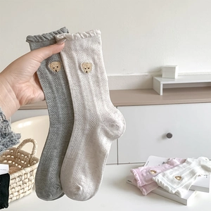 Détail de la broderie ours et du bord à dentelle sur les chaussettes en coton tricoté