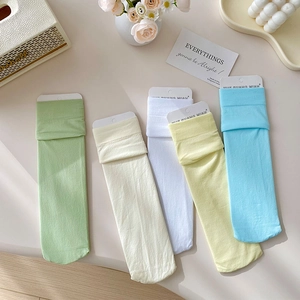 Five pairs of candy-colored velvet crew socks in pastel macaron tones on a cozy background