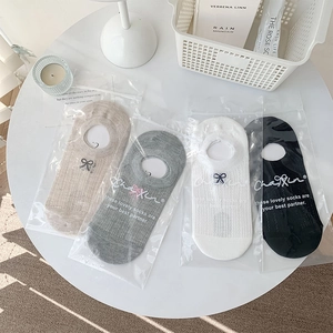Detail of four pairs of breathable mesh low-cut socks with bow embroidery in a home setting