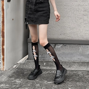 Detail of hollow diamond pattern black calf socks with white bows and lace-up design