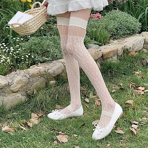 Close-up of white lace thigh-high socks with hollowed-out crochet patterns and mesh detail