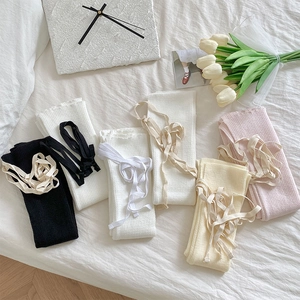 Scaldamuscoli in maglia con nastri in nero, bianco, rosa e beige su piano