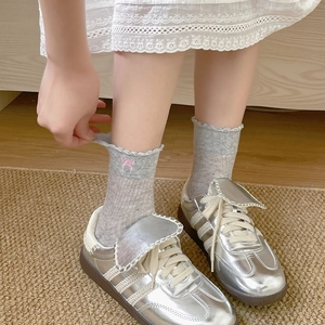 Detailsicht hellgrauer Socken mit Spitzenbesatz und rosa Schleifenbestickung