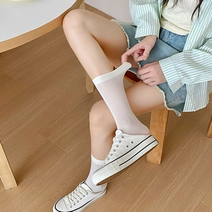 Close-up of pure white velvet mid-calf socks paired with classic white canvas shoes