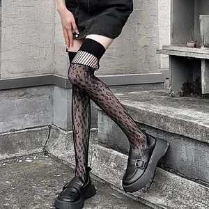 Detail of black over-the-knee mesh socks with horizontal cutouts and diamond patterns