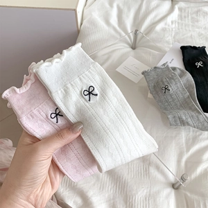 Detailed embroidery of black bows on cotton mesh socks with ruffled edges