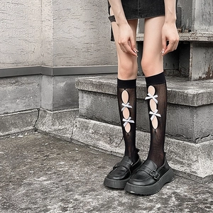 Detail of black hollow-out Lolita socks featuring white silk bows and platform loafers
