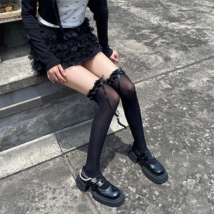 Détail de chaussettes hautes noires avec bordure en dentelle et nœuds avec chaussures Mary Jane