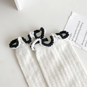 Detail of white mesh knit socks featuring ruffled edges and black contrast trim design