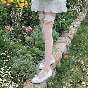 Detail of white lace over-the-knee socks with hollow vertical lines and floral patterns
