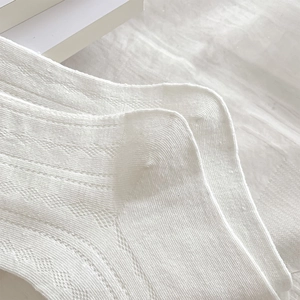 Detail of white cotton socks showing intricate diamond knit pattern and reinforced heel