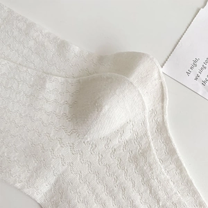 Close-up of white breathable mesh socks with wavy knit texture and elegant ruffled edges