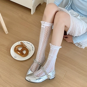 Détail de chaussettes hautes blanches en dentelle ajourée avec nœud et bord à volants