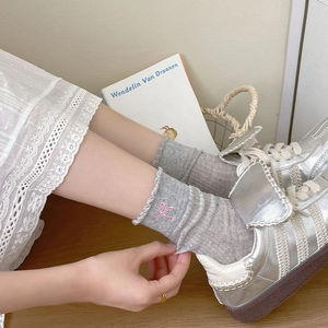 Detailaufnahme grauer Socken mit Spitzenbesatz, rosa Schleife und Rippstrickmuster