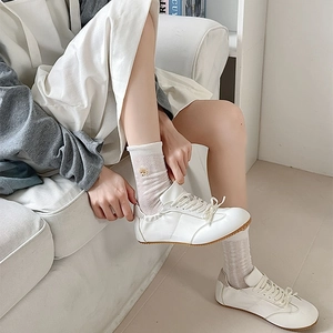 Gros plan sur des chaussettes blanches en maille avec broderie ours et baskets