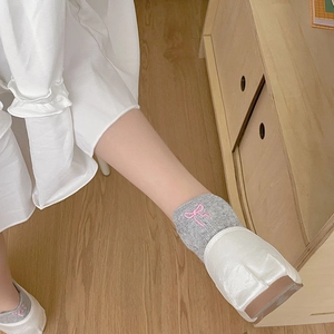 Gros plan de chaussettes grises avec broderie nœud rose et ballerines blanches élégantes