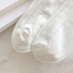 Close-up of white knit socks featuring detailed hollow diamond mesh and soft cotton texture