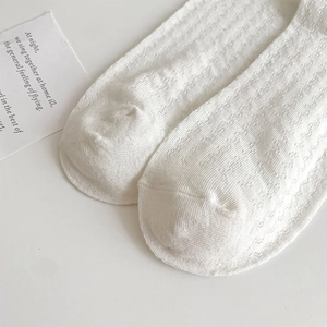 Close-up of white mesh hollow knit socks showing intricate diamond eyelet texture