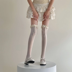 Détail de chaussettes hautes crème avec volants en dentelle et nœuds en ruban de soie