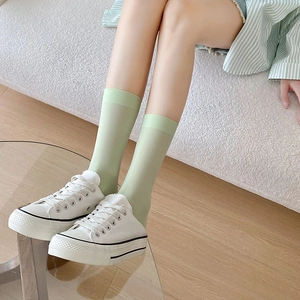 Light green sheer crew socks with elastic cuffs paired with white canvas shoes