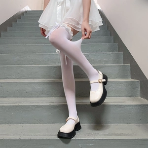 Détail de chaussettes hautes blanches avec froufrous en dentelle et nœuds en ruban