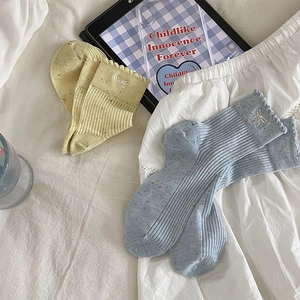 Detail von Spitzen-Baumwollsocken mit Schleifen in sanften Macaron-Farben